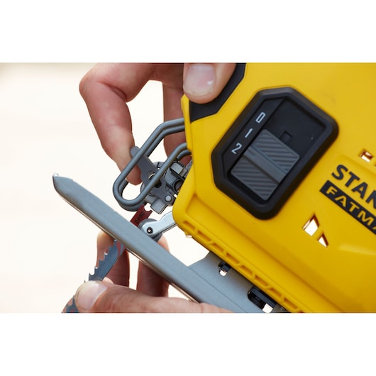 Close-up of a hand adjusting the blade on a yellow STANLEY FatMax power tool.