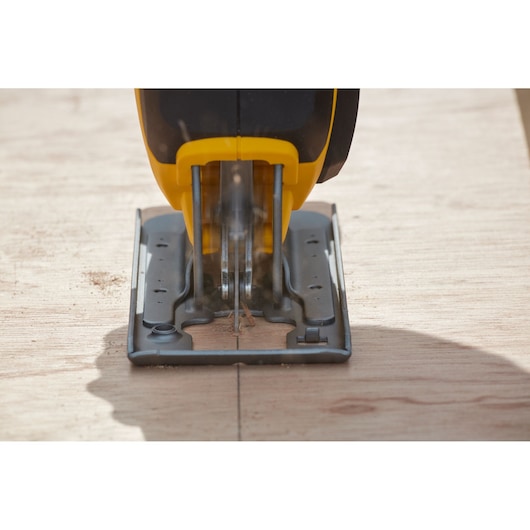 STANLEY SFMCS600D1K jigsaw cutting wood, front angle, yellow and black tool in action.