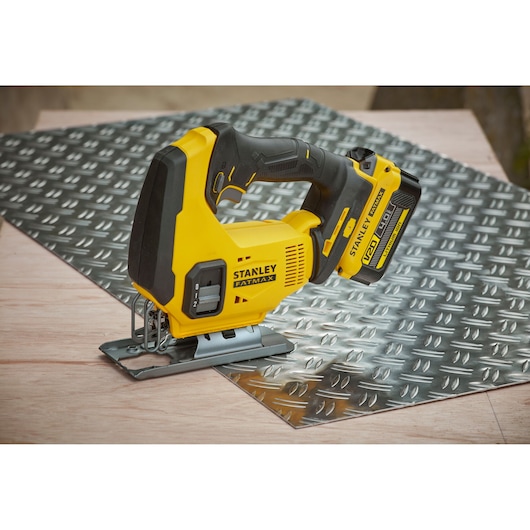 STANLEY SFMCS600M1K cordless jigsaw in yellow and black on metal sheet and wood surface.