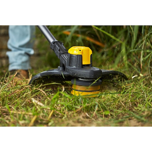 Photo of STANLEY SFMCSTB933M grass trimmer head cutting grass, close-up outdoor view.