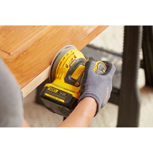 Photo of STANLEY SFMCW220M1S cordless sander in use sanding wooden surface.