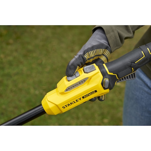 STANLEY SFMSTB930M brushless trimmer handle close-up, yellow and black design, gloved hand holding.