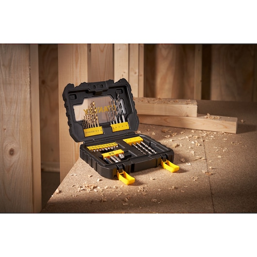 Stanley drill and bit set in black case with yellow clips on a workbench in a wood workshop.
