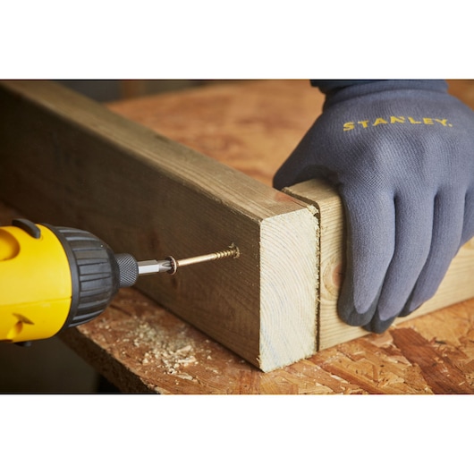 STANLEY STA88560 photography of gloved hand holding wood while a drill drives a screw into the joint.