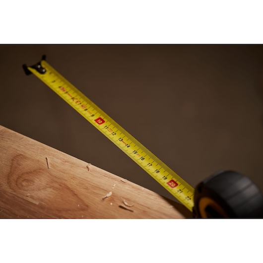 STANLEY STHT0-33559 tape measure extended across wood, close-up angle showing metric scale.