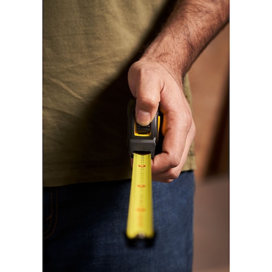STANLEY STHT0-33559 tape measure held in hand, yellow blade extended, close-up photography.