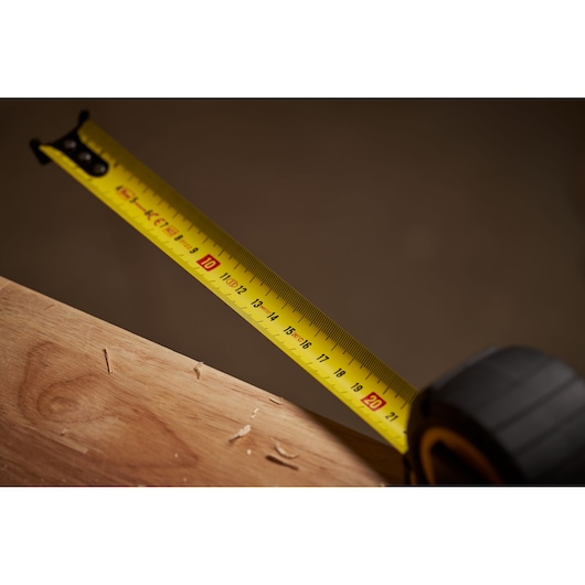 STANLEY STHT0-33561 tape measure extended on wood surface, close-up side angle.