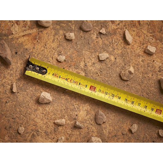 STANLEY STHT0-33561 tape measure photography on a dusty surface with scattered rocks.