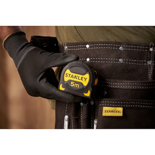 STANLEY STHT0-33561 tape measure, black and yellow, in tool belt, photography close-up.