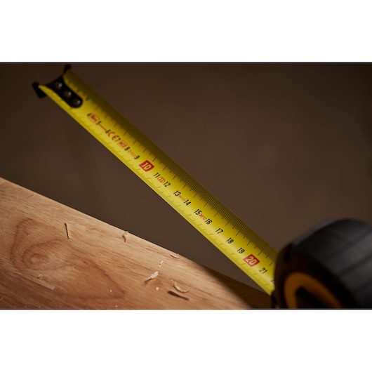 STANLEY STHT0-33566 tape measure close-up on wood, yellow blade with black markings.