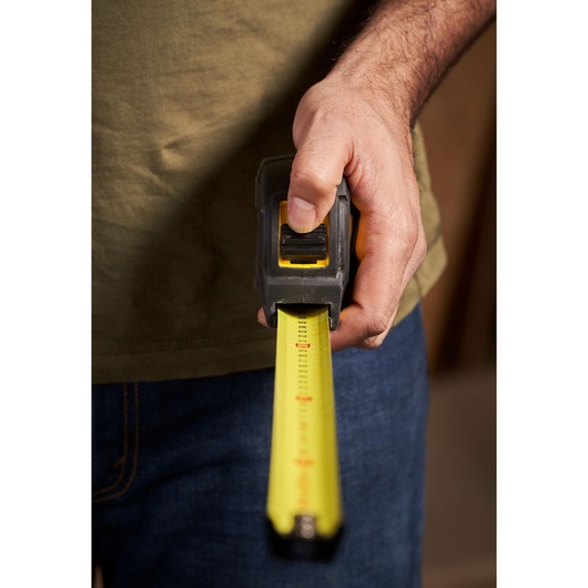 Photo of STANLEY STHT0-33566 tape measure in hand, yellow blade extended, front view.