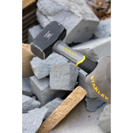 Photo of STANLEY STHT0-54127 mini sledge hammer with gray and yellow handle breaking concrete blocks.
