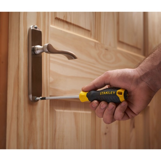 Stanley STHT0-62144 screwdriver used to fasten a screw on a wooden door handle.