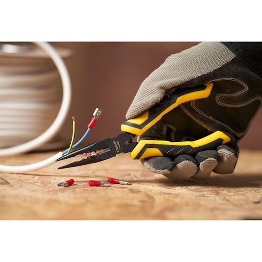 STANLEY STHT0-74364 pliers with yellow and black handles held by gloved hand, gripping electrical wire.