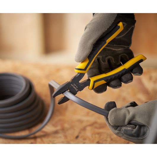 Photo of STANLEY STHT0-74367 pliers cutting plastic tubing, worker wearing gloves.