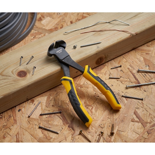 STANLEY STHT0-75067 cutting pliers with yellow and black handles on wood, surrounded by nails and wires.