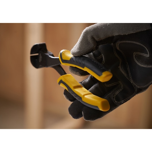 STANLEY STHT0-75067 diagonal cutting pliers with yellow and black handles held in gloved hand, close-up.