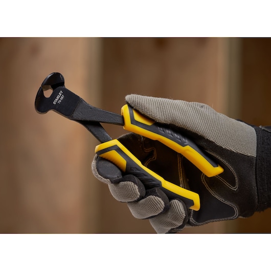 Photo of STANLEY STHT0-75067 nipper pliers with yellow handles held in a gloved hand.