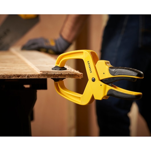 STANLEY STHT0-83200 spring clamp holding wood on workbench, close-up during woodworking.