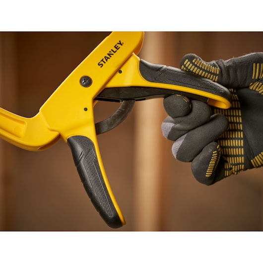 Photo of STANLEY STHT0-83200 one-handed clamp held by a gloved hand, close-up view.