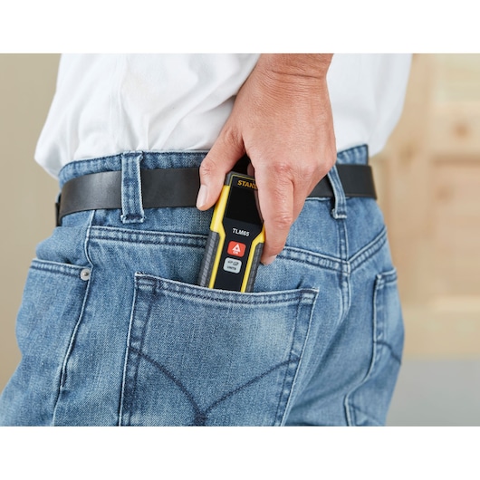 STANLEY STHT1-77032 laser distance measurer held in hand, placed in denim jeans back pocket.
