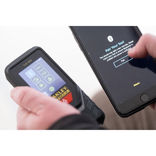 STANLEY STHT1-77142 laser measurer being paired with a smartphone via Bluetooth, close-up view.