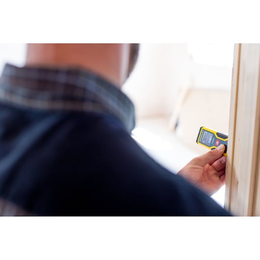 STANLEY STHT1-77409 laser range finder used by person for wood measurement, close-up photography.