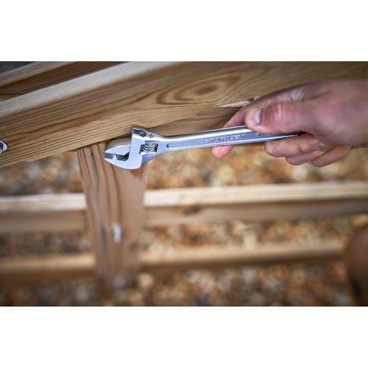 STANLEY STHT13121-0 adjustable wrench in use on wooden structure, close-up photography.