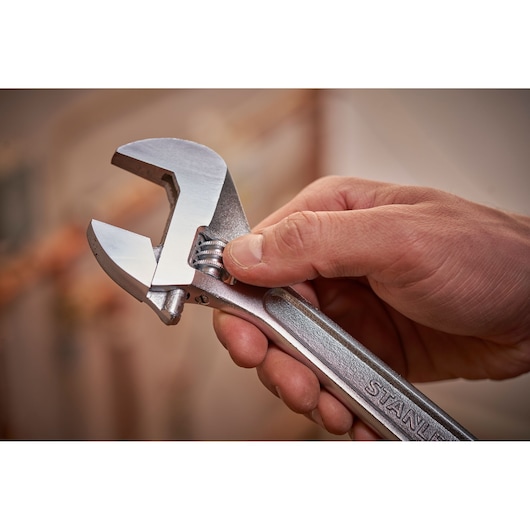 STANLEY STHT13156-0 adjustable wrench held in hand, close-up showing metal finish and jaw adjustment.