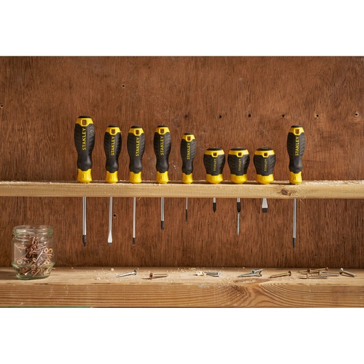 STANLEY STHT16154-0 screwdriver set with black and yellow handles, nine pieces on wooden shelf, front view.