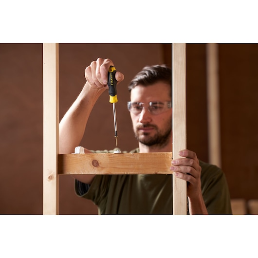 Photo of a person using a STANLEY STHT16163-0 screwdriver to fasten a screw into a wooden frame.