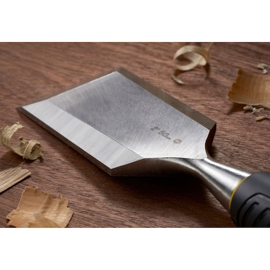STANLEY STHT16737-0 woodworking chisel close-up with sharp blade on wood surface and wood shavings.