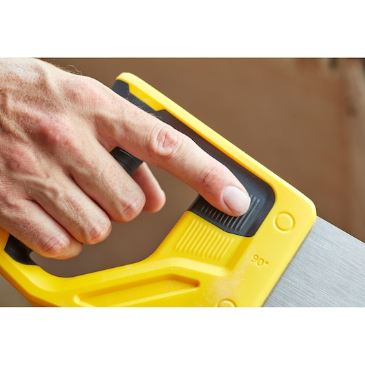 STANLEY STHT20348-1 hand saw yellow handle close-up with finger on black grip.