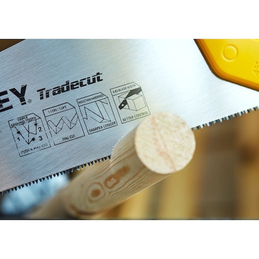 STANLEY STHT20349-1 hand saw close-up cutting wood, showing Tradecut blade details.