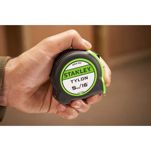 STANLEY STHT30602-1 tape measure Tylon 5m/16ft, black and green, held in hand, front view.