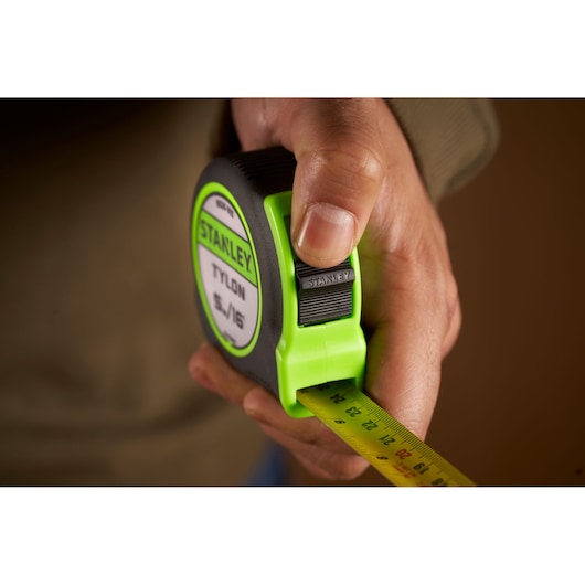 Photo of STANLEY STHT30602-1 tape measure in hand, showing lock button and yellow measuring blade.