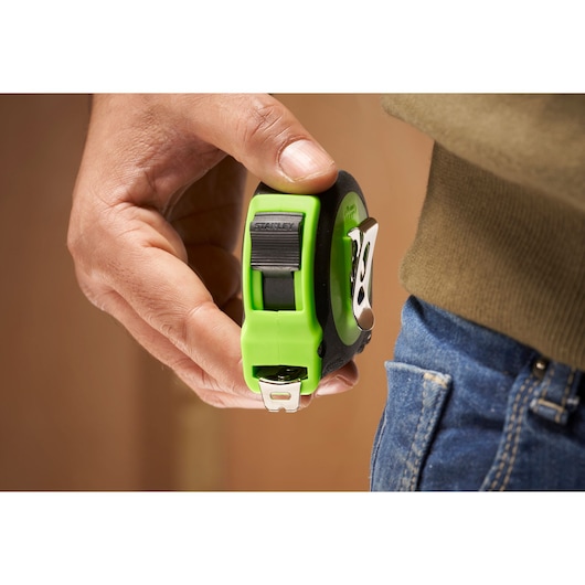 STANLEY STHT30602-1 tape measure with green casing held near jeans pocket, side angle.