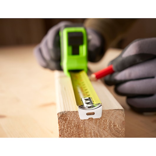 STANLEY STHT30604-1 tape measure on wood, close-up, gloves and pencil marking measurements.