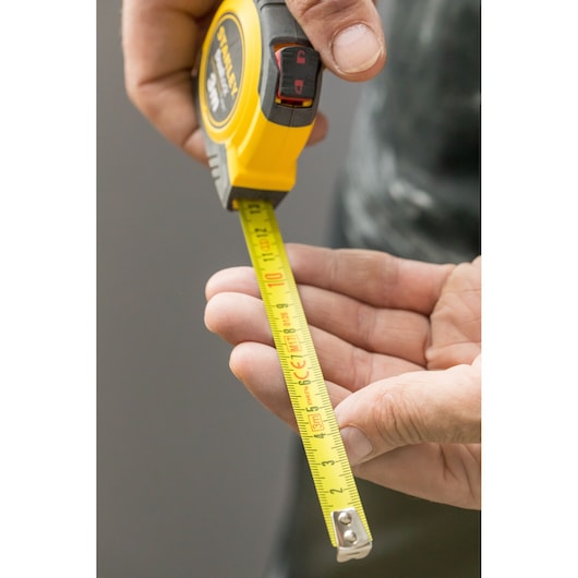 STANLEY STHT36806-0 tape measure, yellow and black, shown in hand extended for measurement.