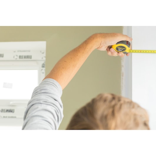 Photo of STANLEY STHT36806-0 tape measure in use, measuring a wall indoors.