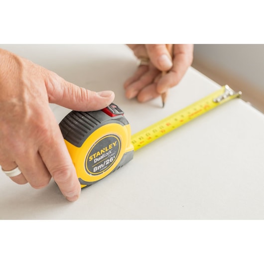 STANLEY STHT36807-0 measuring tape in use, yellow case with black accents, extended on a white surface.