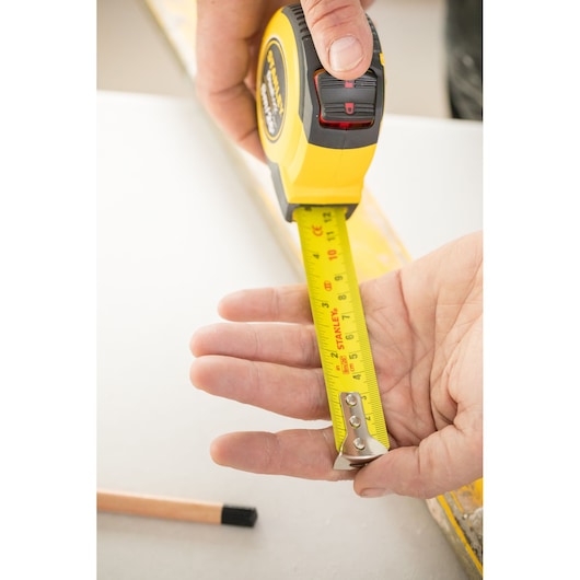 Photo of STANLEY STHT36807-0 yellow tape measure extended across a hand, close-up during use.