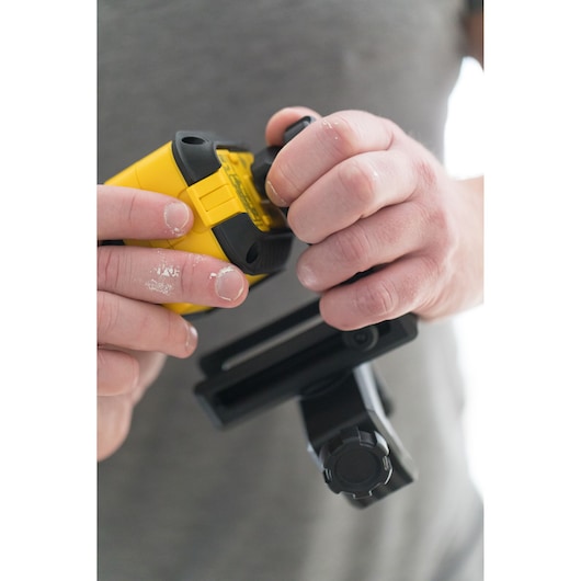 STANLEY STHT77503-1 laser level held and adjusted by hand, close-up photography, yellow and black design.