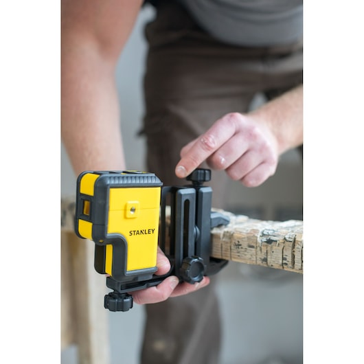 STANLEY STHT77503-1 laser level attached to a wooden beam, user adjusting mounting bracket.