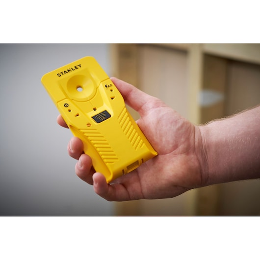 STANLEY STHT77587-0 yellow stud finder held in hand, front view, photography product.