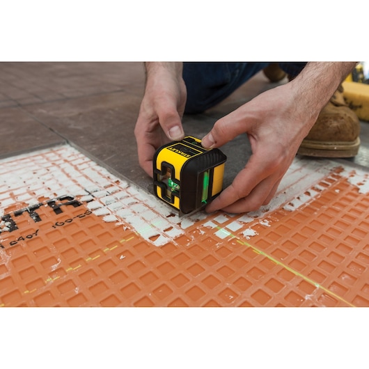 Photo of a STANLEY STHT77592-1 laser level placed on a floor with orange tiling mat.