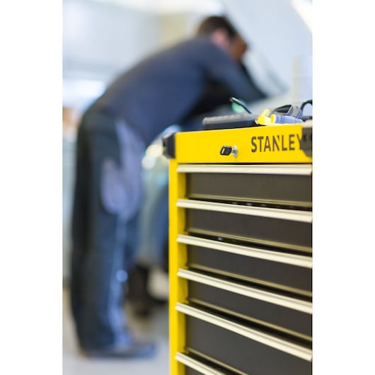 STANLEY STMT1-74306 tool chest with yellow front and metal drawers, photographed from side in workshop.