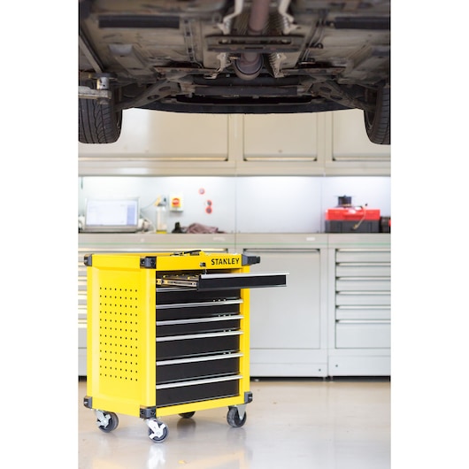 STANLEY STMT1-74306 yellow rolling tool cabinet with open drawer in workshop, side angle.