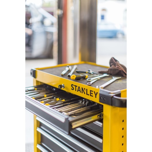 STANLEY STMT1-74306 yellow tool cabinet with open drawer and hand tools, side angle photo.