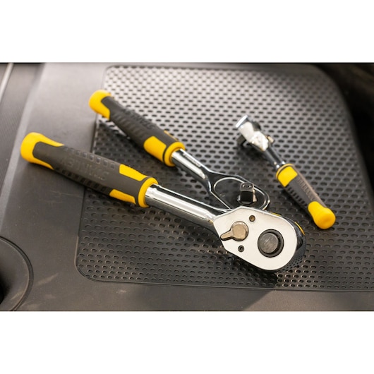 Stanley ratchet wrenches with yellow and black handles placed on a textured black surface.